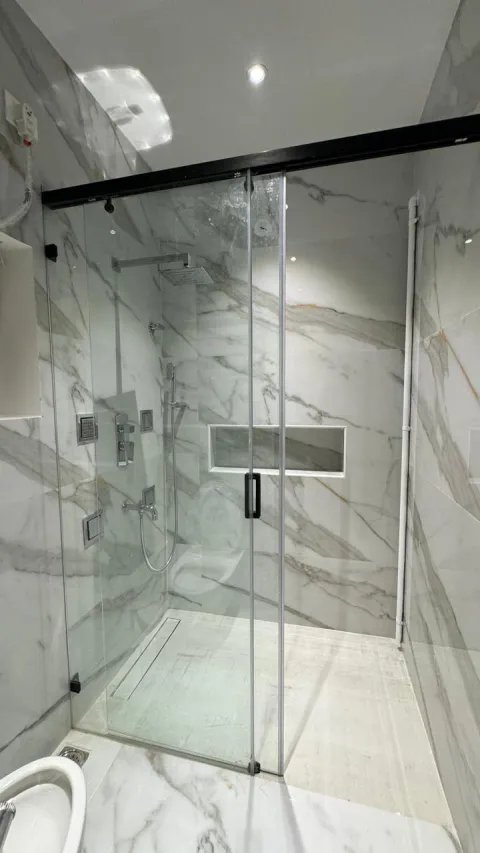 Bathroom with glass shower partition and marble tiles